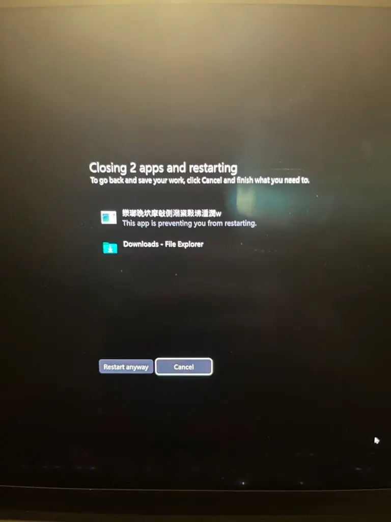 Photo of a laptop screen showing a "Closing 2 apps and restarting" message